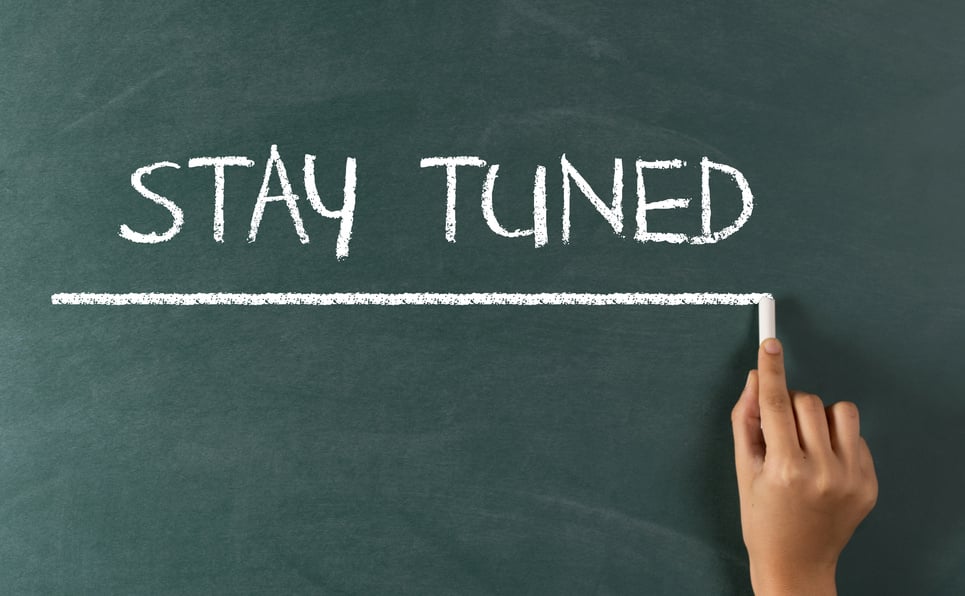 Hand Writing "STAY TUNED" on Blackboard